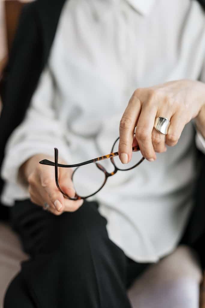 Close-up of a woman holding glasses, symbolizing thought and professionalism. How a Female Business Coach Helps You Scale Smarter (Not Harder)