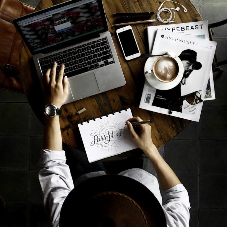 Top view of a creative workspace with laptop, coffee, and hand lettering for design inspiration. What Is a Marketing Service? A Deep Dive Into the Digital Strategies That Actually Grow Your Business