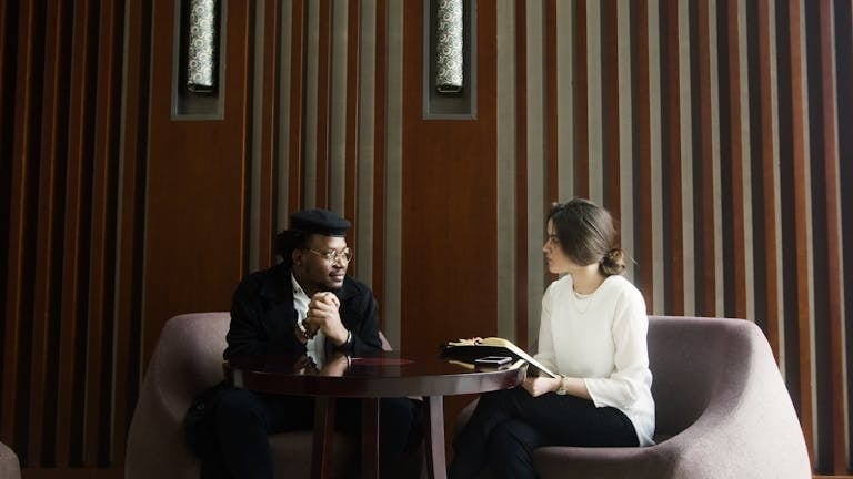 A professional business meeting between a man and woman in a stylish, modern office setting. Fractional CMO