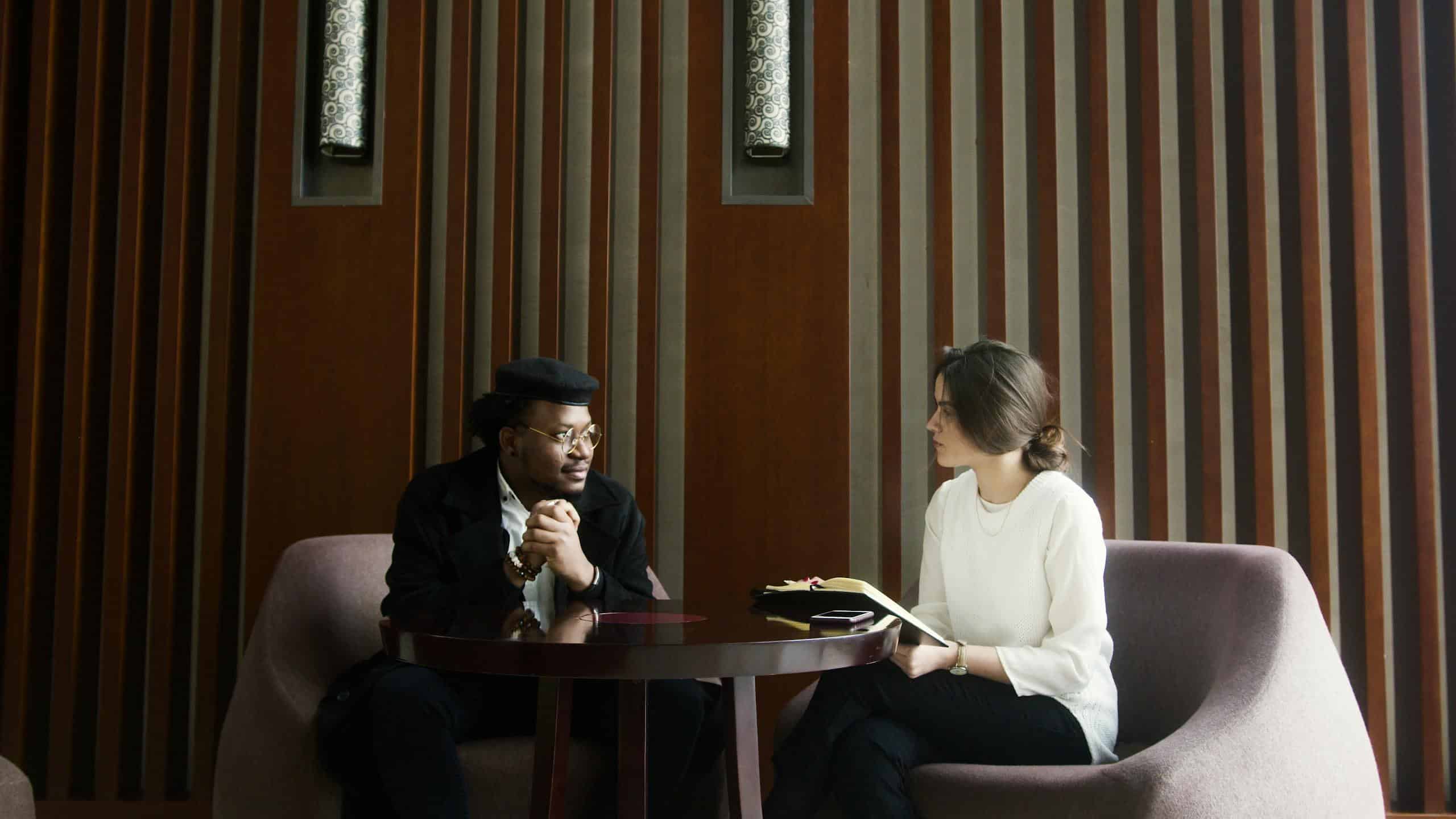 A professional business meeting between a man and woman in a stylish, modern office setting. Fractional CMO