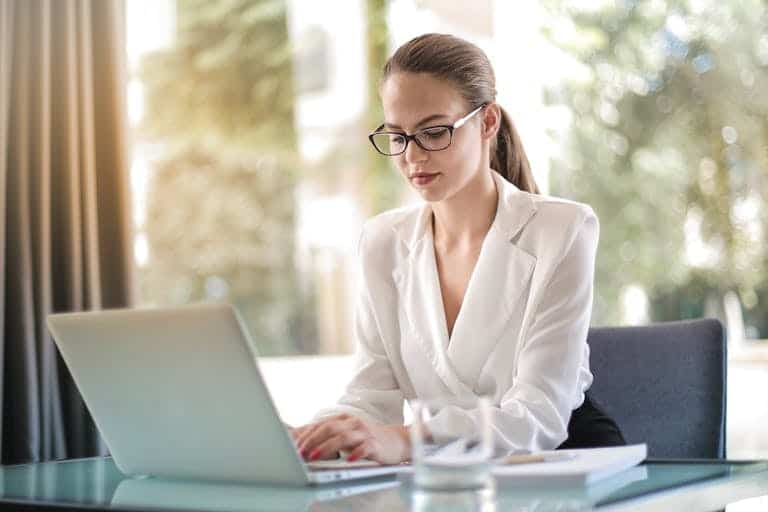 Confident businesswoman using a laptop at her desk, focused on her work. Fractional CMO