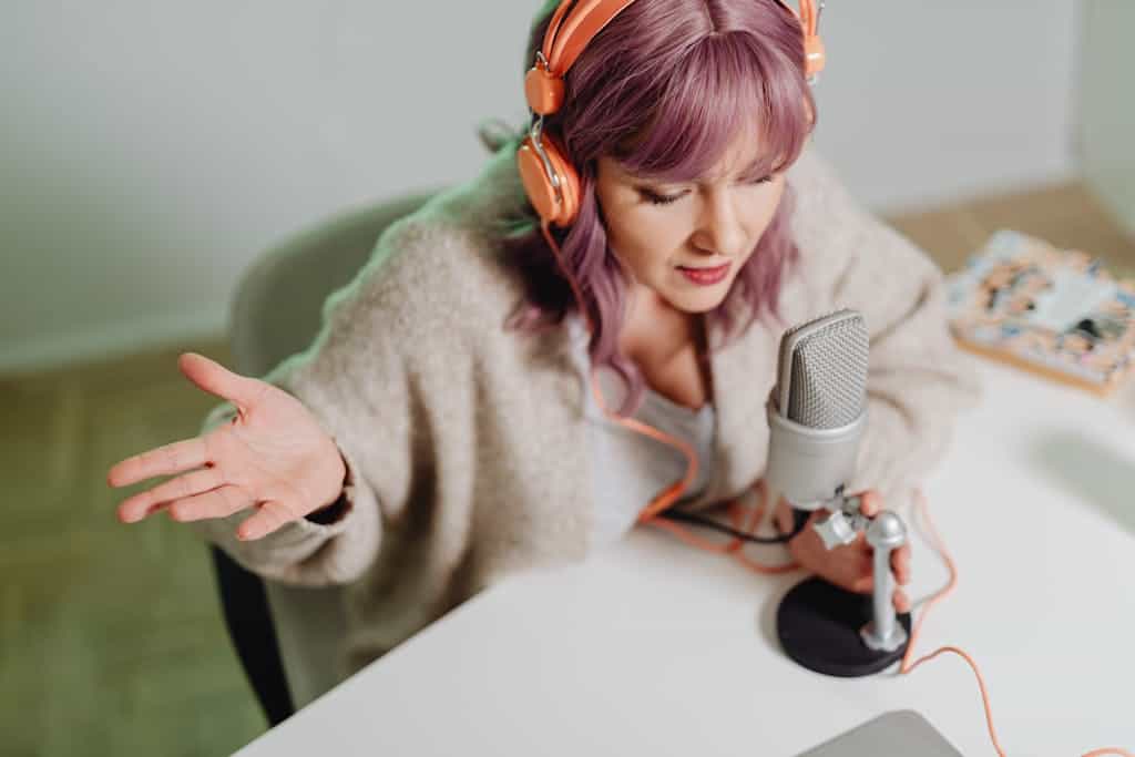 Woman using headphones and microphone to record a podcast indoors. BRAND Voice, Brand Vibes