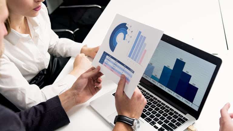 Business professionals discussing data charts and graphs in a modern office setting. Digital Strategy