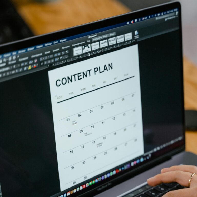 Close-up of hands typing on a laptop displaying a content plan document, ideal for business or marketing content.