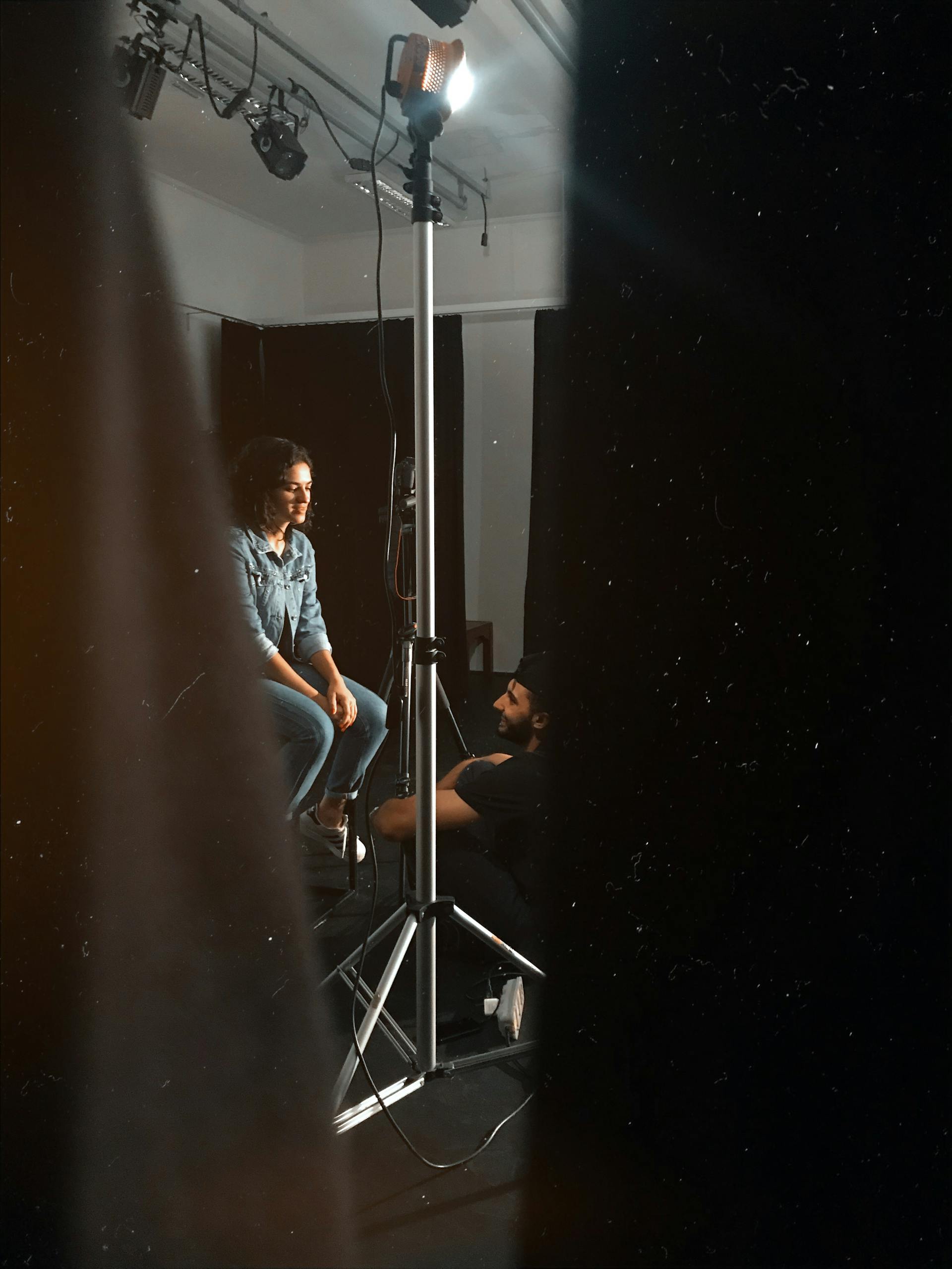 Intimate backstage moment in a studio with spotlight and tripod focus.