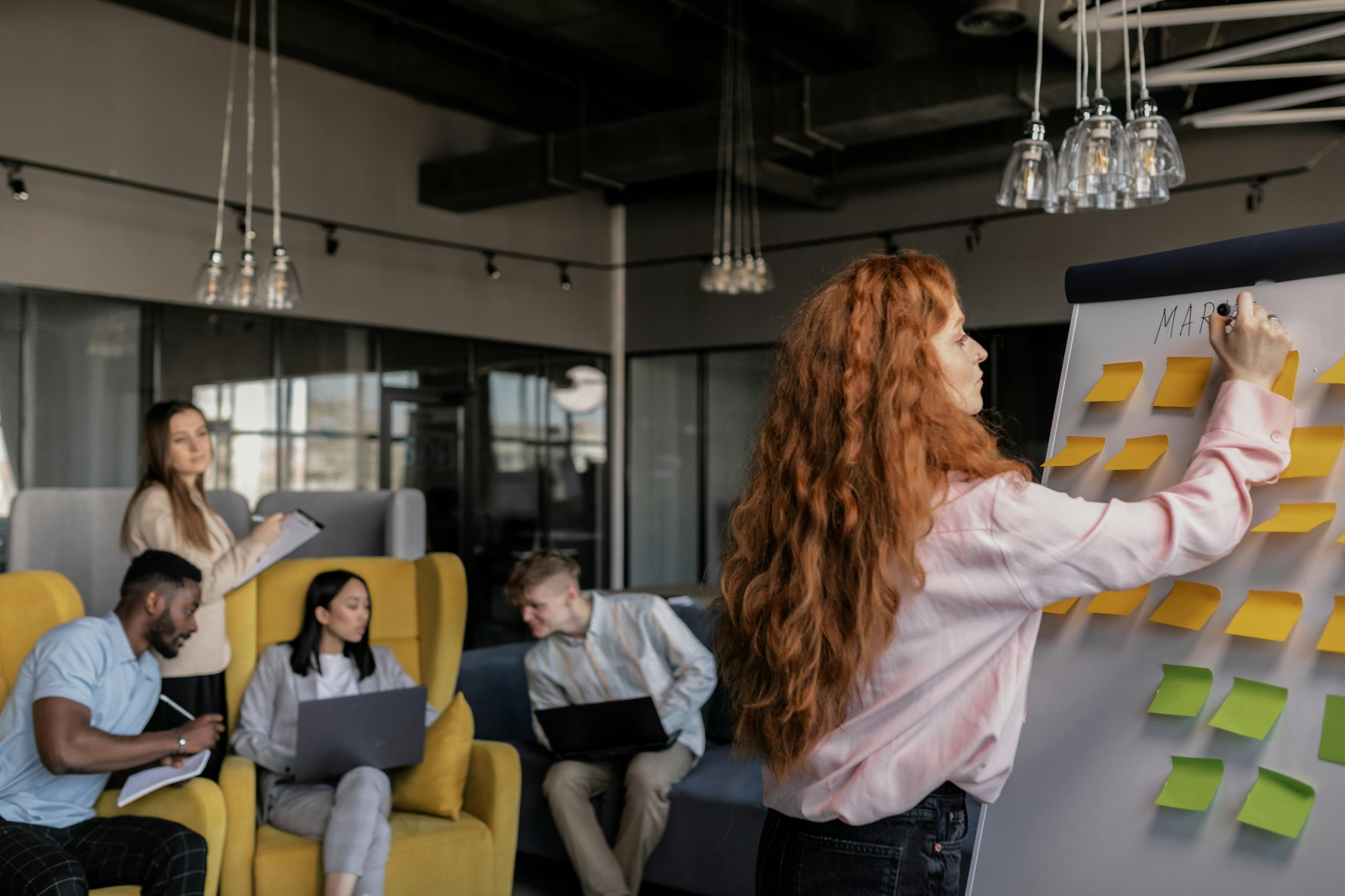 Team members collaborating in a modern office, focusing on strategy and planning using sticky notes.