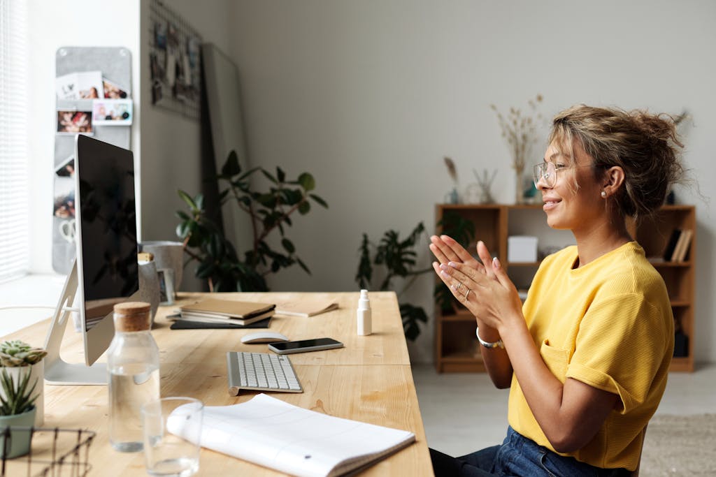Woman smiling and clapping hands in a cozy home office environment.