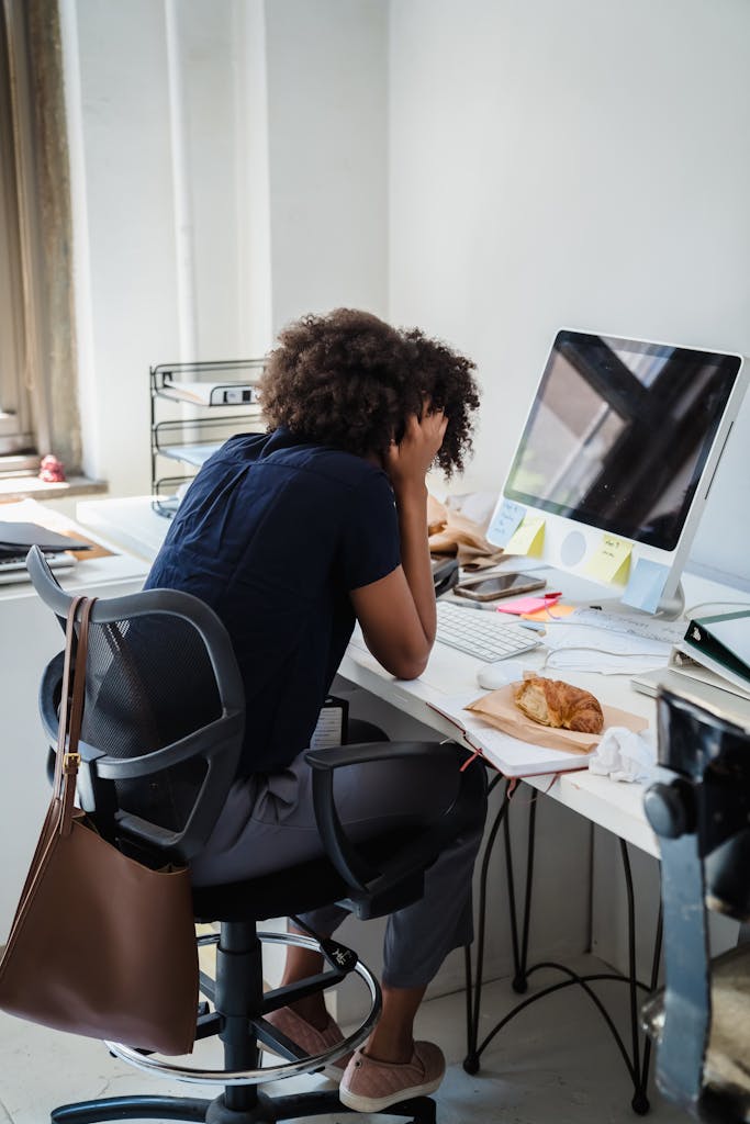 Businesswoman showing stress while working at her desk in an office setting.